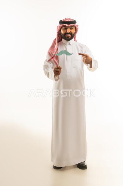 Saudi Man in Traditional Thobe Holding Mustache Prop