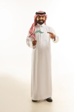 رجل سعودي بالزي التقليدي يمسك شارب ورقي