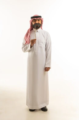 رجل سعودي بالثوب التقليدي يمسك شارب ورقي