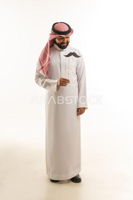 Saudi Man in Traditional Thobe Holding Mustache Prop