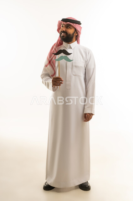 رجل سعودي بالزي التقليدي يحمل إكسسوارات شارب ورقية