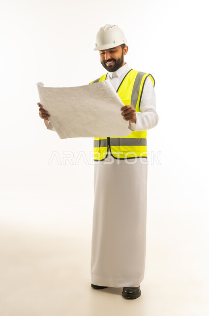 مهندس سعودي بالثوب يمسك مخططات هندسية في الاستوديو