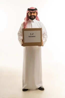 رجل سعودي يحمل صندوق تبرعات على خلفية بيضاء
