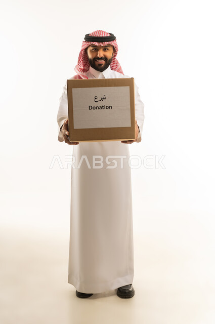 رجل سعودي بالزي التقليدي يحمل صندوق تبرعات