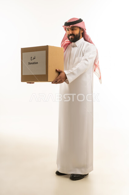 رجل سعودي بالزي التقليدي يحمل صندوق تبرعات