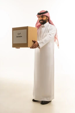 رجل سعودي بالزي التقليدي يحمل صندوق تبرعات