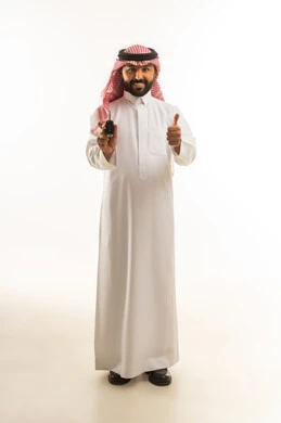 رجل سعودي بالزي التقليدي يحمل مفتاح سيارة وإشارة الإعجاب