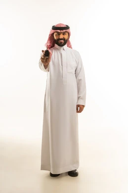 رجل سعودي بالزي التقليدي يمسك مفتاح سيارة بخلفية بيضاء