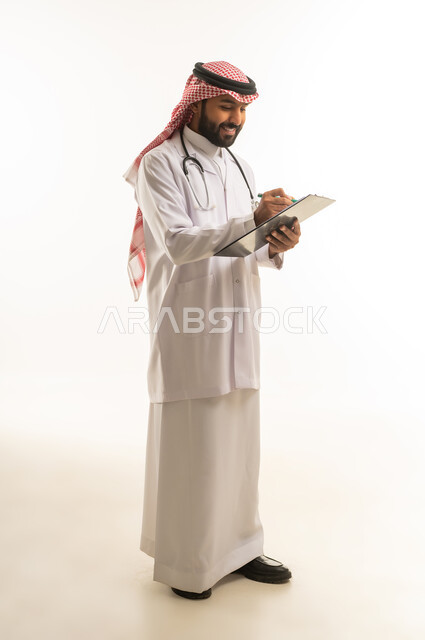 طبيب سعودي يكتب على لوحة ملاحظات بالزي الطبي