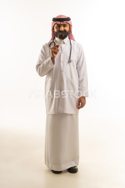 طبيب سعودي بالمعطف الأبيض يحمل شارباً ورقياً