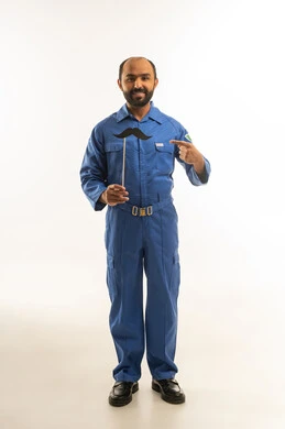 فني سعودي بزي عمل أزرق يحمل شارب ورقي