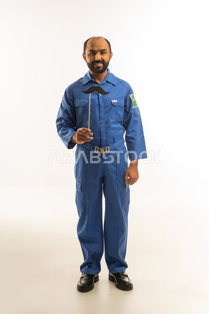 فني سعودي بزي أزرق مع شارب صناعي