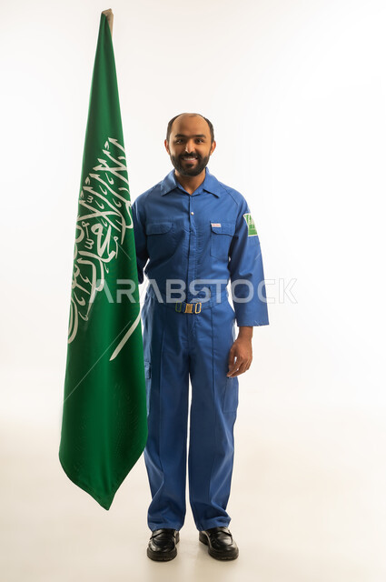 عامل سعودي بزي العمل الأزرق مع العلم السعودي