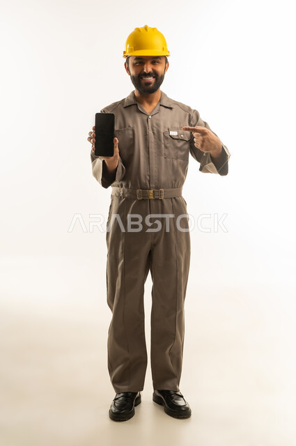 عامل سعودي بزي رسمي يحمل هاتف ذكي