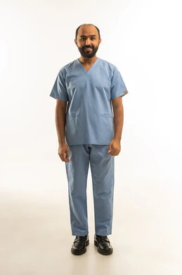 طبيب سعودي بالزي الطبي الأزرق على خلفية بيضاء