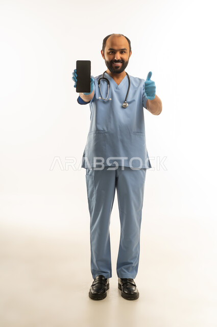 طبيب سعودي يحمل هاتف ذكي مع إيماءة الإبهام