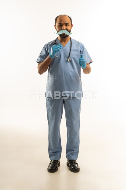 Saudi Male Doctor in Blue Scrubs Holding Mustache Prop
