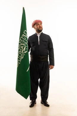 رجل بالزي الكردي يحمل علم المملكة العربية السعودية