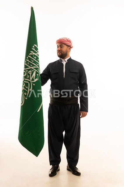 رجل بالزي الكردي التقليدي يحمل علم المملكة العربية السعودية