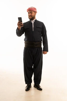 رجل كردي بالزي التقليدي يستخدم الهاتف الذكي