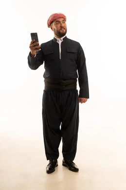 رجل كوردستاني بالزي التقليدي الأسود يحمل هاتفاً