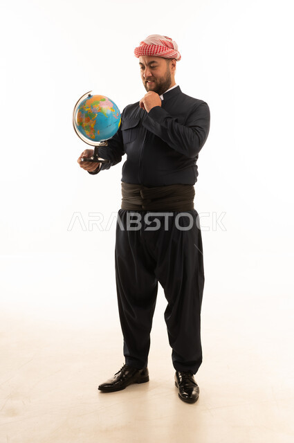 رجل كوردي بالزي التقليدي يحمل كرة أرضية