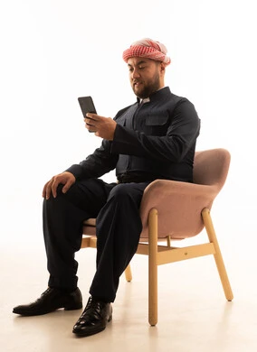 رجل بالزي الكردي والشماغ السعودي يستخدم الهاتف خلفية بيضاء