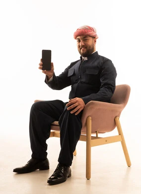 رجل كردي بالزي التقليدي يحمل هاتف ذكي