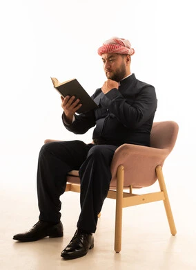 رجل كردي بالزي التقليدي الأسود يقرأ كتاباً