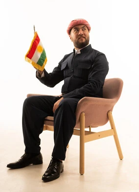 رجل كردي بالزي التقليدي يحمل العلم في الاستوديو