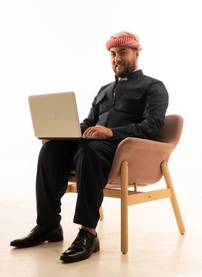 رجل كردي بالزي التقليدي الأسود يستخدم اللابتوب