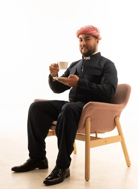 رجل بالزي الكردي التقليدي الأسود مع فنجان قهوة