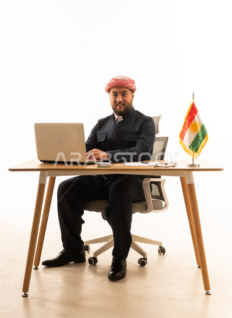 رجل كردي في المكتب مع لابتوب وعلم كردستان