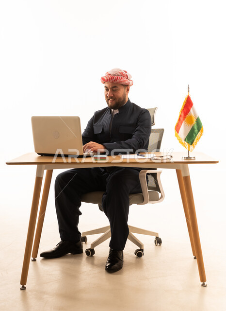 رجل كوردستاني يعمل على لابتوب في مكتب بخلفية بيضاء