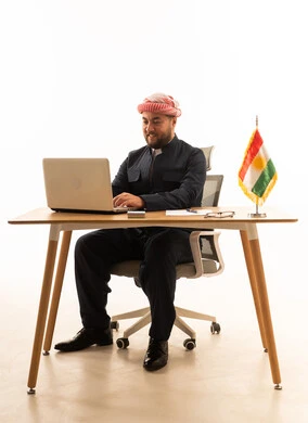 رجل كوردستاني يعمل على لابتوب في مكتب بخلفية بيضاء