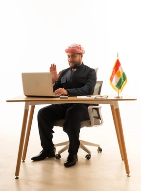 رجل بالزي الكوردي التقليدي يستخدم المحمول على المكتب