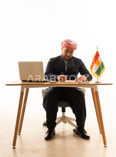 رجل أعمال كردي باللباس التقليدي يكتب على مكتب عمل