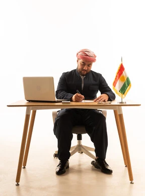 رجل أعمال كردي باللباس التقليدي يكتب على مكتب عمل
