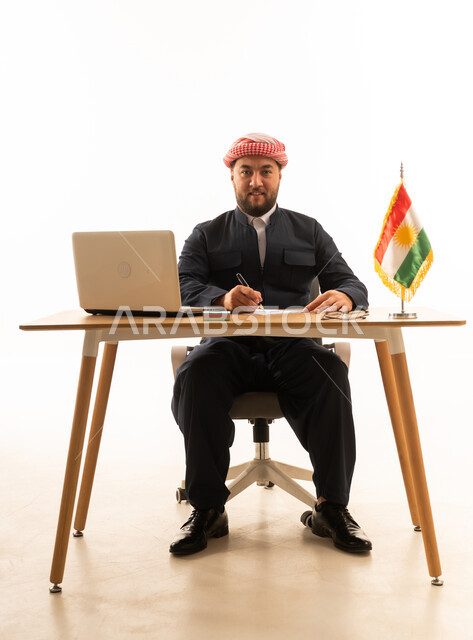 رجل كردي بالزي التقليدي يجلس خلف مكتب عمل