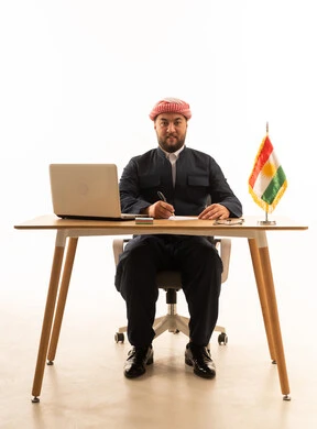 رجل كوردستاني في مكتب عمل مع حاسوب وعلم