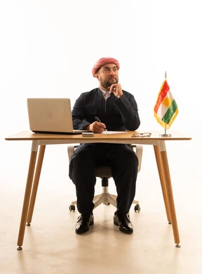Kurdish Businessman at Desk with Flag and Laptop