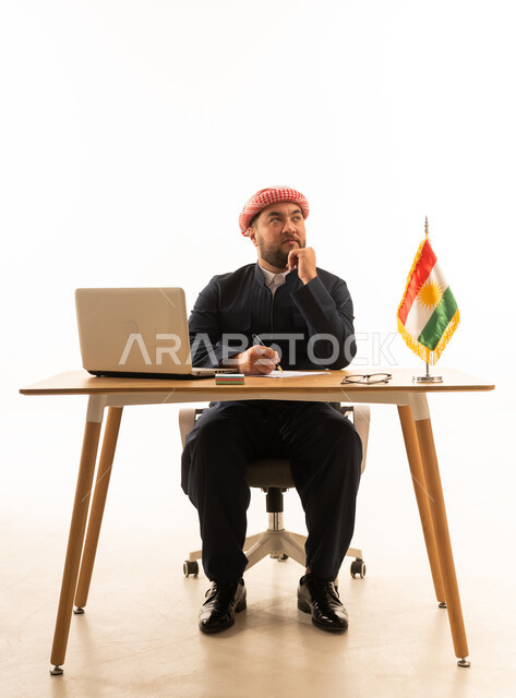 رجل كردي بالزي التقليدي يفكر خلف مكتب العمل