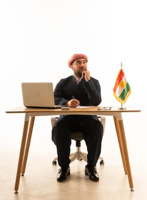 رجل كردي بالزي التقليدي يفكر خلف مكتب العمل