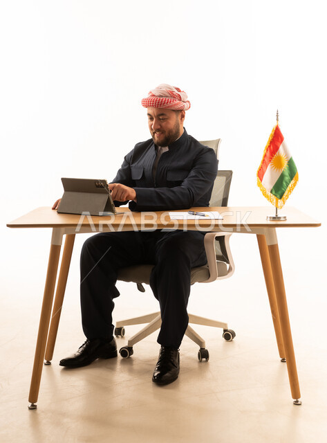 Kurdish Man in Traditional Attire Using Tablet at Desk