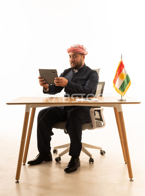 Kurdish Man in Traditional Dress Using Tablet at Desk