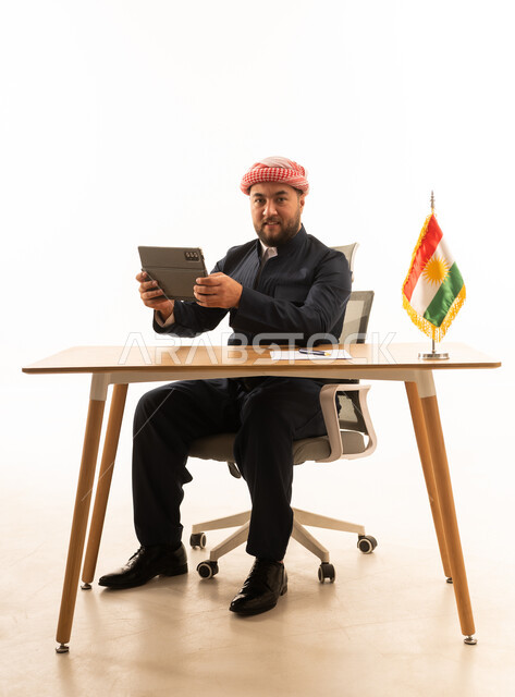 Kurdish Businessman with Tablet and Flag at Desk