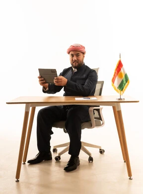 رجل أعمال كردي مع جهاز لوحي وعلم على المكتب