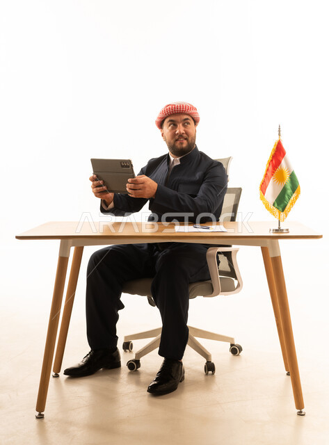 رجل باللباس الكردي التقليدي مع جهاز لوحي وعلم كردستان