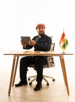 رجل باللباس الكردي التقليدي مع جهاز لوحي وعلم كردستان