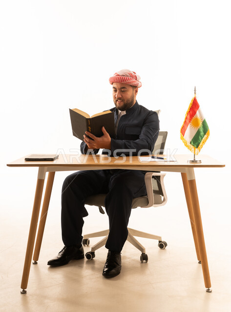 رجل كردي بالزي التقليدي يقرأ على المكتب